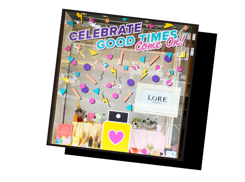 lore perfumery window with confetti coming out of a perfume bottle and celebrate good times come on