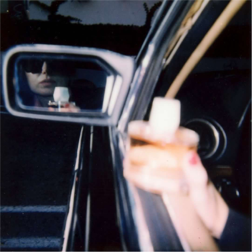 photo of woman in car holding sonic flower by room 1015 seeing herself and the fragrance in the side mirror