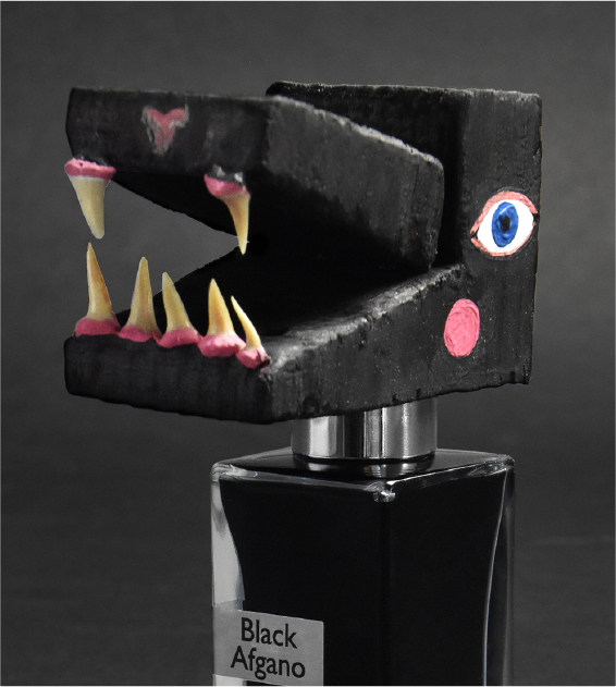 bottle of black afgano by nasomatto with a paper dinosaur head